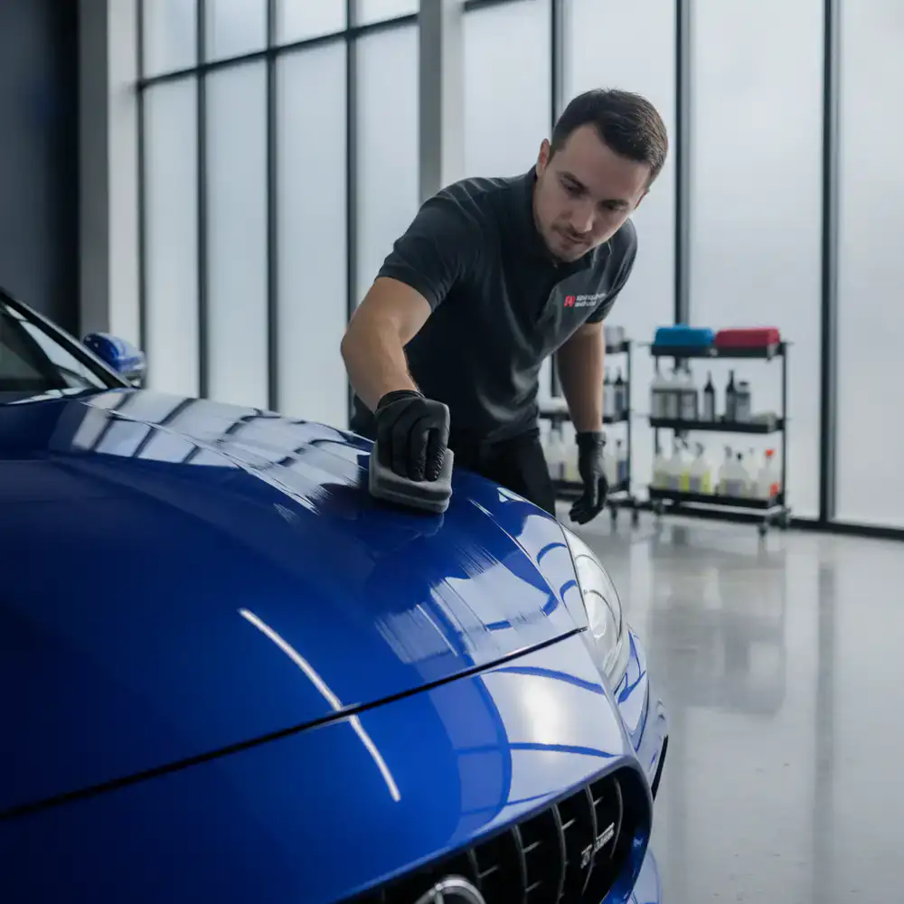 Professional meticulously applying ceramic coating to a vehicle